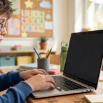 Child learning touch typing on a laptop with correct home row finger placement
